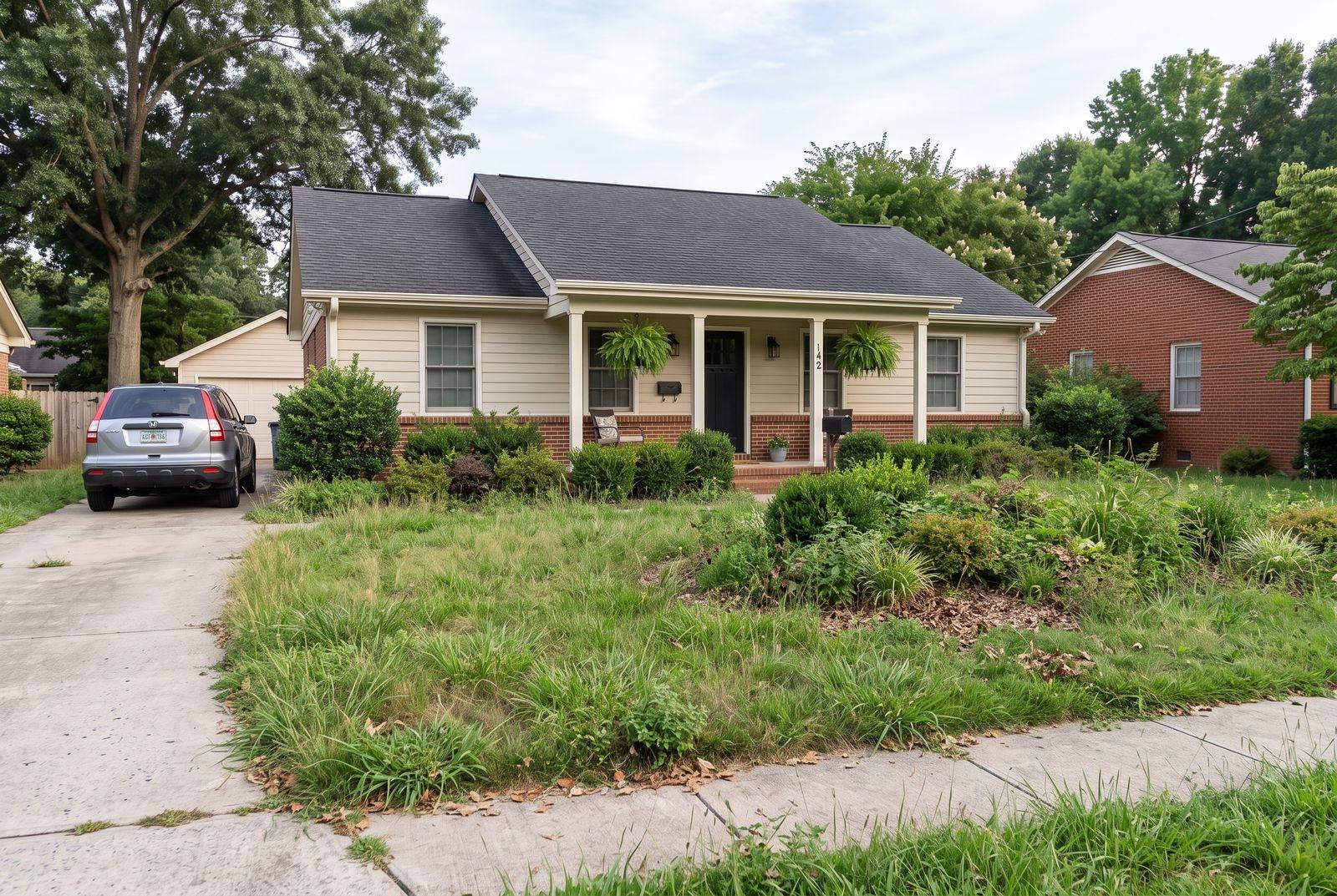 The same Nicholson, GA front yard before landscaping: overgrown patchy lawn, ragged edges, and weedy garden bed